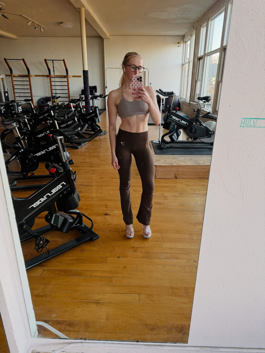 Coach Libby in her gym wearing a neutral sports top and brown leggings
